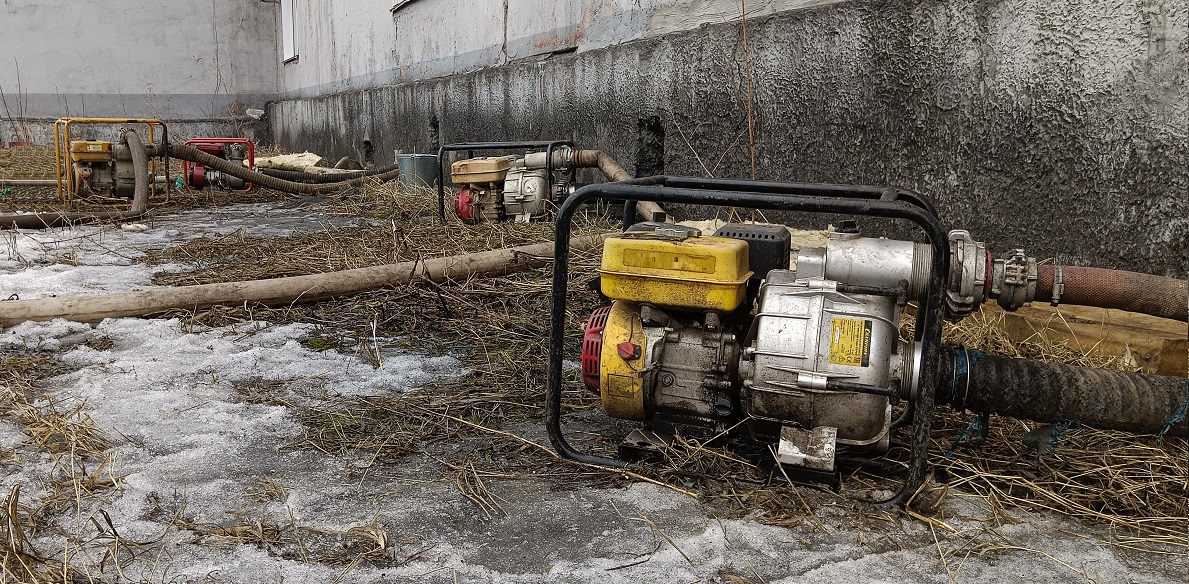 Откачка мотопомпами талой воды из подвала дома в Саяногорске
